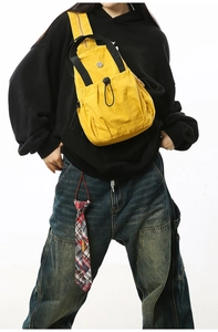 Model wearing a bright yellow nylon crossbody bag with black adjustable strap and drawstring