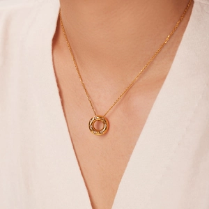 Close-up of 18K gold hollow ring pendant with zircon inlay worn on a model neckline