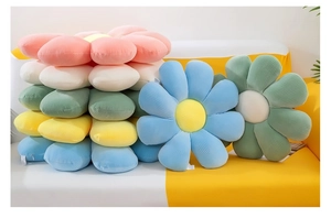 Close-up of soft plush daisy cushions in pink white and blue stacked on a cozy sofa