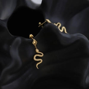Detailed view of gold snake-shaped earrings with diamond stud and textured scale patterns