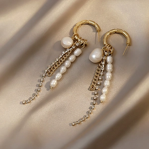 Golden bamboo hoop earrings with baroque pearls and rhinestone tassels on champagne silk
