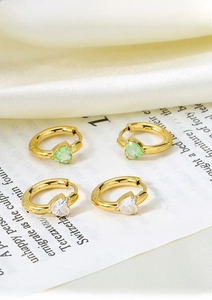 Macro detail of titanium steel heart hoop earrings with green and clear zircon stones