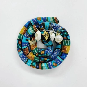 Detailed view of colorful dreadlock hair tie with butterfly, shell, and pearl charms