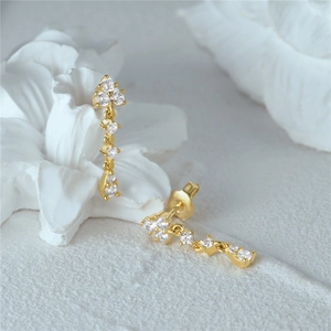 Macro view of gold floral drop earrings with clear cubic zirconia on white stone