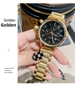 Close-up of golden stainless steel watch with black dial and chronograph details