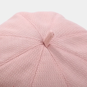 Detailed top view of pink knitted beret showing woven texture and stitched panels