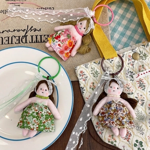 Three cute floral dress doll plush keychains with lace and beads on white plate