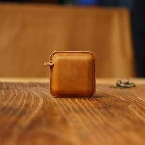 Macro shot of vintage brown leather tape measure case on dark wood background