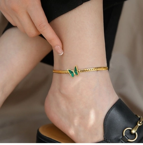 Close-up of 18K gold plated snake chain anklet with green enamel butterfly charm