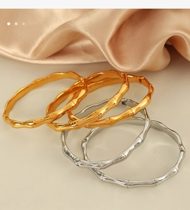 Elegant gold and silver bamboo joint bracelets arranged on a luxury silk background