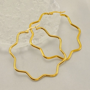 Detail of 18K gold wave pattern hoop earrings on textured glass with snap-post closure