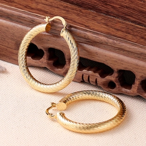 Orecchini a cerchio dorati con trama a coste a spirale su un elegante sfondo materico