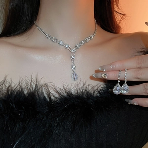 Macro shot of silver teardrop necklace and matching earrings set on elegant woman