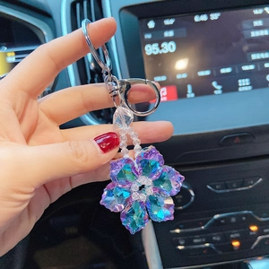Detail shot of a purple crystal flower keychain held in hand inside a car interior