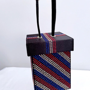 Detail of evening clutch bag featuring diagonal rhinestone stripes and rope handles