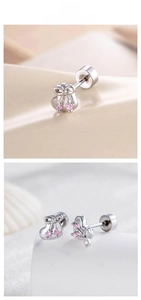 Detail of silver bow earrings with pink zircon stones on a beige textured background