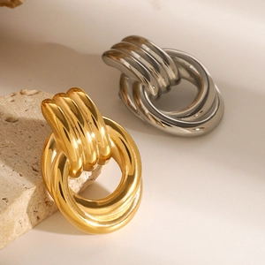 Intertwined double hoop earrings in gold and silver finish on a natural stone base