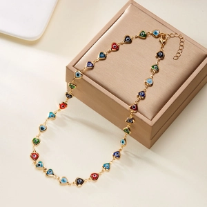 Detailed close-up of golden necklace featuring colorful heart-shaped evil eye bead charms