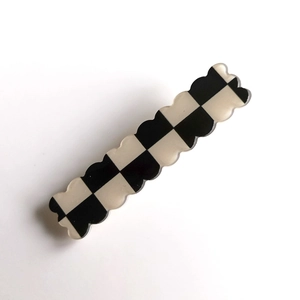 Close-up of black and white checkerboard hair clip with wavy edges on white background