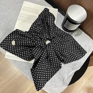 Macro shot of polka dot fabric scrunchie with bow detail and white shell charm accessory