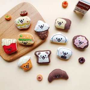 Flat lay of cute cartoon food plush toys including fries and croissant on wood board