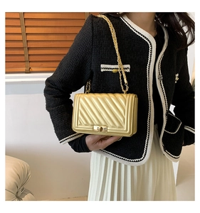 Close-up of golden quilted crossbody bag featuring a metal chain strap and twist lock