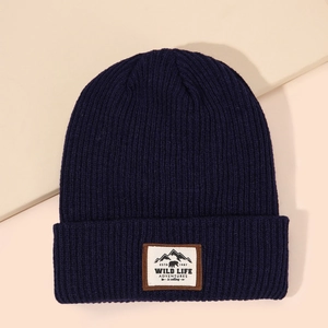 Detailed close-up of navy knit beanie with mountain and bear patch on ribbed fabric