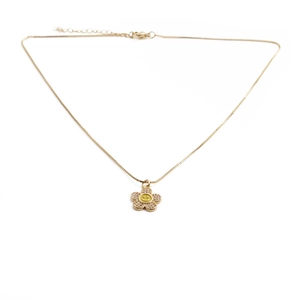 Close-up of golden necklace with zircon flower pendant and yellow smiling face center