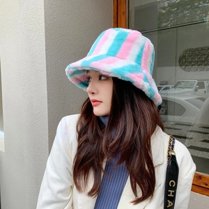 Close-up of fuzzy rainbow striped bucket hat for women in a stylish city street setting