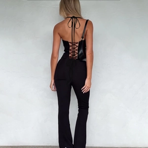 Detail showing the sexy backless design and crisscross lace-up straps on black bodysuit