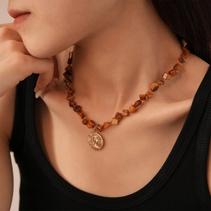 Vintage necklace with brown resin beads and gold embossed coin pendant on model