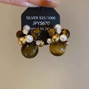 Macro shot of 925 silver stud earrings with amber tiger eye, pearls and small rhinestones