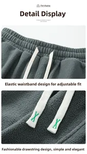 Dettaglio dell'elastico in vita e coulisse con ricamo verde su pantaloni in pile grigio