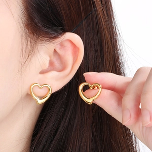 Golden hollow heart stud earrings shown on model for stylish stainless steel jewelry look