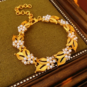 Detail of vintage gold bracelet with flower motifs, faux pearls, and sparkling crystals