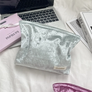 Macro detail of silver velvet makeup bag with textured pleats and white brand label