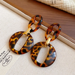 Detail of tortoiseshell acrylic oval earrings with polished golden metal links and posts