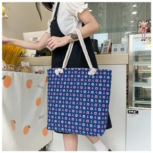 Detail of nautical print canvas tote bag featuring anchor motifs and thick rope handles