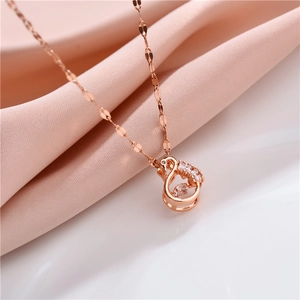 Detailed close-up of rose gold swan necklace with sparkling zircons on pink silk fabric