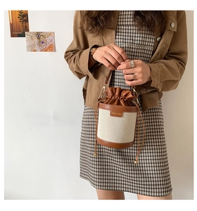 Detail of vintage canvas bucket bag with brown leather trim and drawstring closure