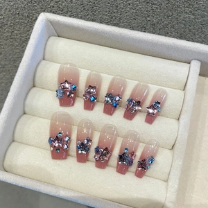 Detail of pink gradient press-on nails with 3D star charms and blue rhinestones