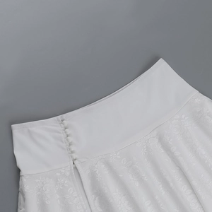 Detailed close-up of white lace skirt featuring button closures and fabric texture