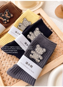 Detailed view of knitted mid-calf socks with shiny rhinestone bear patches in four colors