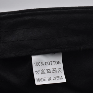Detailed view of the 100% cotton wash care label and made in China tag on a black hat