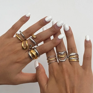 Close-up of stacked gold and silver bicolor stainless steel rings with organic wave design