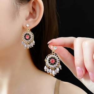 Detail of floral earrings with pink crystals and lavender teardrop tassels on model