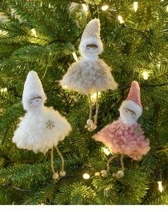 Close-up of three plush Christmas angel dolls in white, beige, and pink on a tree
