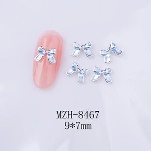 Détail d'un bijou d'ongle nœud bleu 9x7mm montrant les dimensions et la pose sur ongle