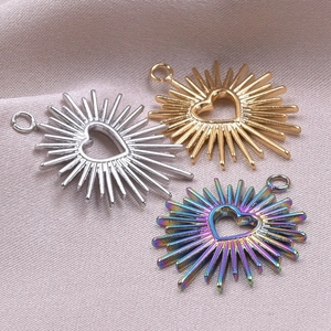 Macro shot of sunburst heart pendants in gold, silver, and rainbow steel finishes