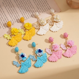 Detailed view of bohemian raffia flower earrings in yellow, white, blue and rose pink